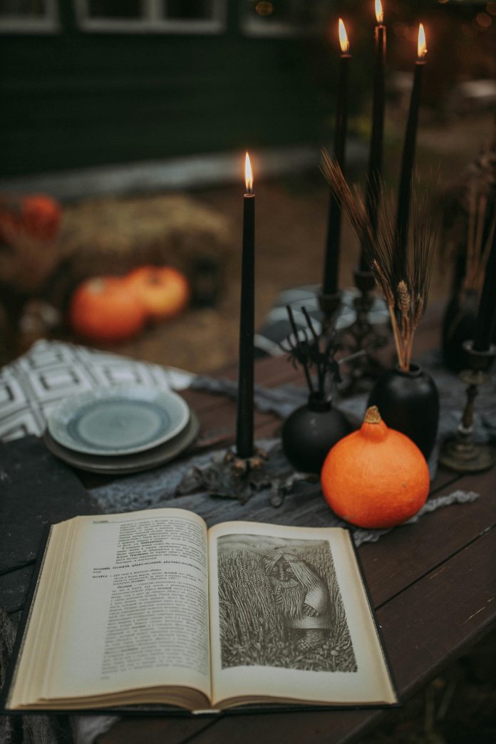 an open occult book with aged pages, surrounded by black lit candles, ritual symbols, and mystical artifacts on a darkened, atmospheric surface.